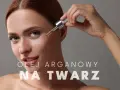 Kobieta aplikuje kroplę olejku arganowego na twarz. Delikatna pielęgnacja dla promiennej cery.