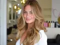 Uśmiechnięta kobieta z blond włosami w stylu wolf cut, z pasemkami i objętością.