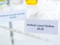 Biały proszek z etykietą "Sodium Lauryl Sulfate (SLS)" obok pipety laboratoryjnej.