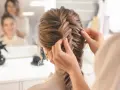 Stylistka tworzy dobierane warkocze. Warkocz rybi ogon jest w trakcie zaplatania, tworząc elegancką fryzurę.