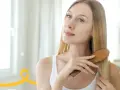 Kobieta szczotkuje włosy, wykonując domowy peeling skóry głowy.