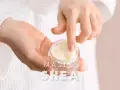 Dłonie zanurzają się w słoiczku z kremem. Masło shea co to? Naturalny kosmetyk do pielęgnacji.