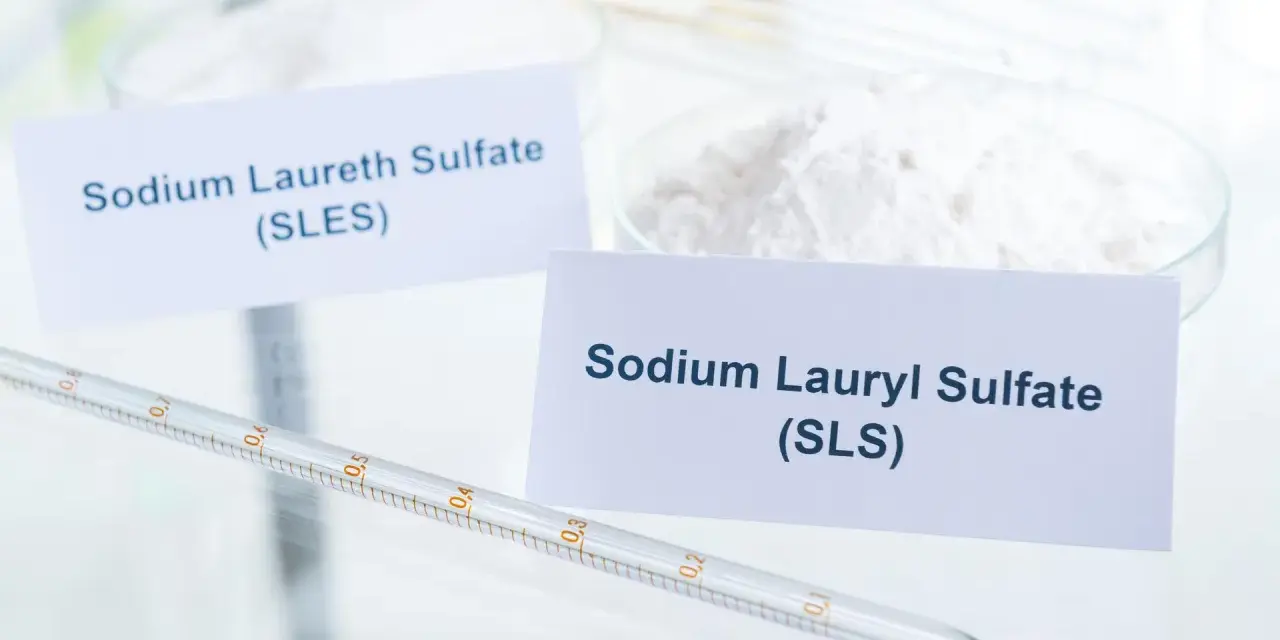 Biały proszek z etykietą "Sodium Lauryl Sulfate (SLS)" obok pipety laboratoryjnej.