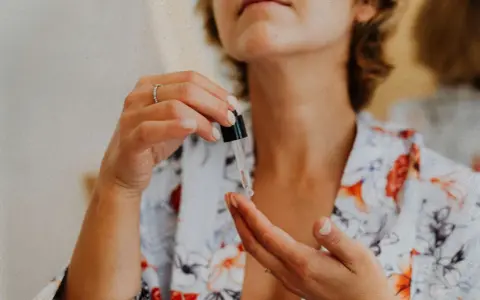 Kobieta aplikuje serum z pipetki na dłoń. Czy peptydy są bezpieczne? To pytanie nurtuje wiele osób dbających o cerę.