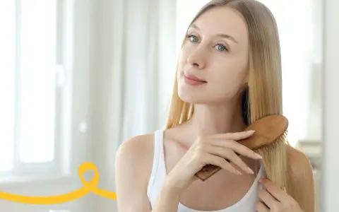 Kobieta szczotkuje włosy, wykonując domowy peeling skóry głowy.