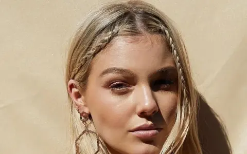 Dziewczyna z blond włosami, warkocz z grzywki krótkie włosy, ozdobne kolczyki.