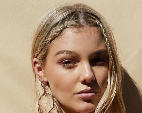 Dziewczyna z blond włosami, warkocz z grzywki krótkie włosy, ozdobne kolczyki.