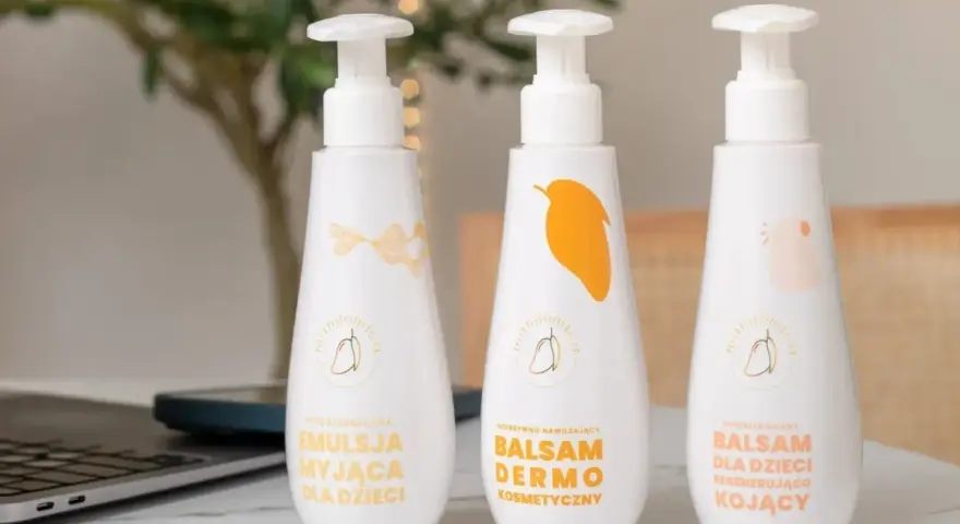 Emolienty co to? Trzy białe butelki z pompką: emulsja myjąca, balsam dermo i balsam dla dzieci. Idealne do pielęgnacji delikatnej skóry.