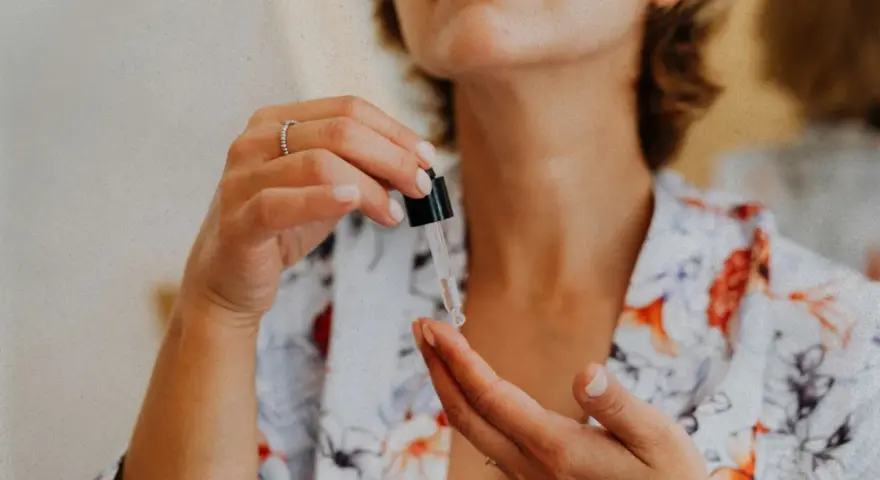 Kobieta aplikuje serum z pipetki na dłoń. Czy peptydy są bezpieczne? To pytanie nurtuje wiele osób dbających o cerę.