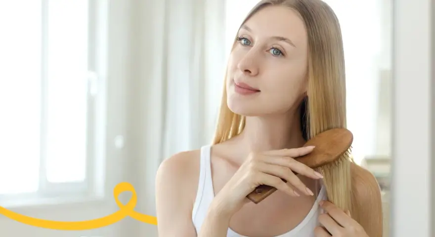 Kobieta szczotkuje włosy, wykonując domowy peeling skóry głowy.
