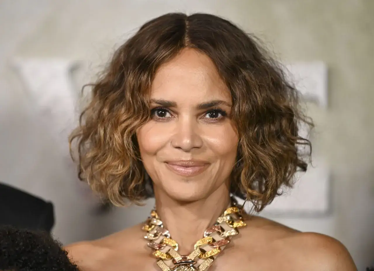 Halle Berry w stylowej fryzurze na boba dla 50 latki, z falowanymi włosami i efektownym naszyjnikiem.