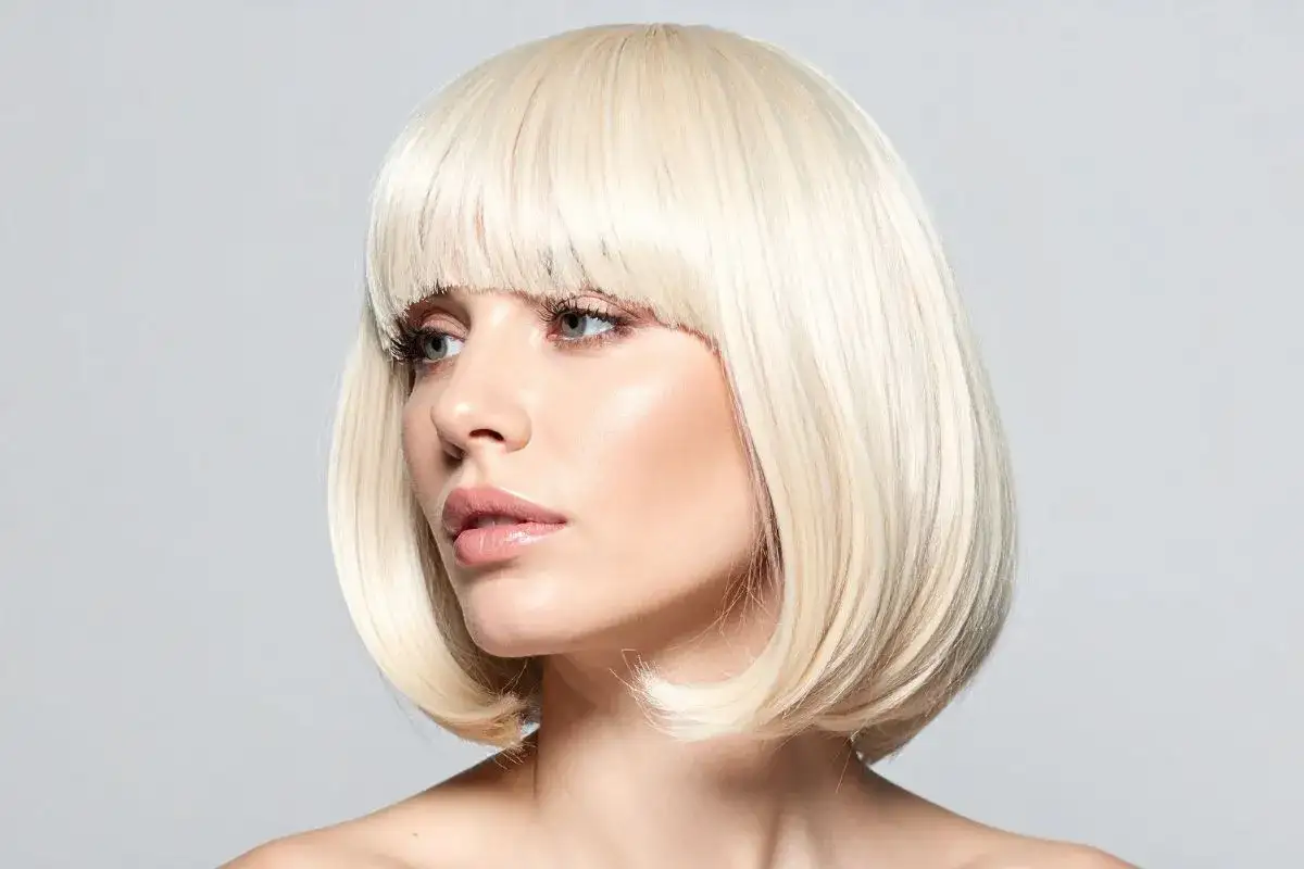 Kr&oacute;tki, cieniowany bob warstwowy w blond odcieniu, podkreślający delikatne rysy twarzy.